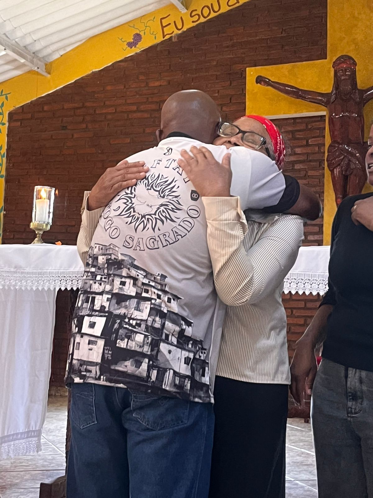 Acolhido abraçando familiar na capela da Comunidade Neftai